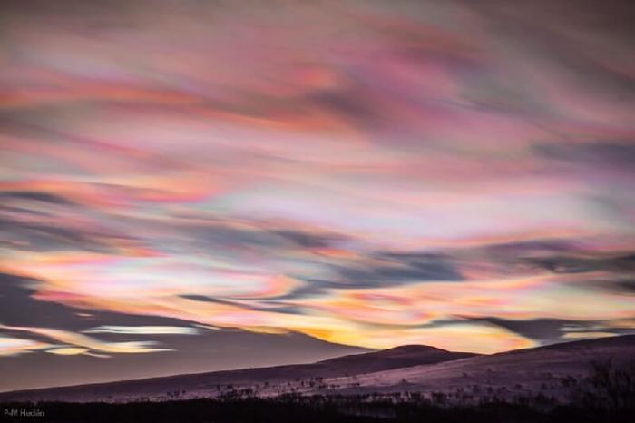 smooth bright wavy clouds blanketing a dark sky, shining with peach, gold, and a little cyan.